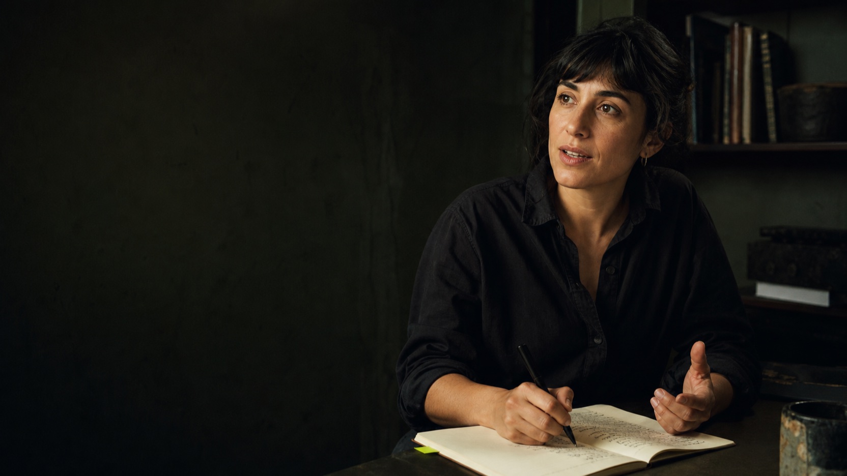 A person speaking and making notes in a quiet studio